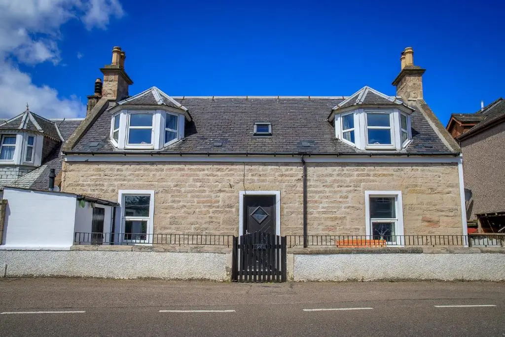 a brick house with a black door on a street at Cosy Cottage in Fishertown, Nairn - Free Parking & Pets welcome in Nairn