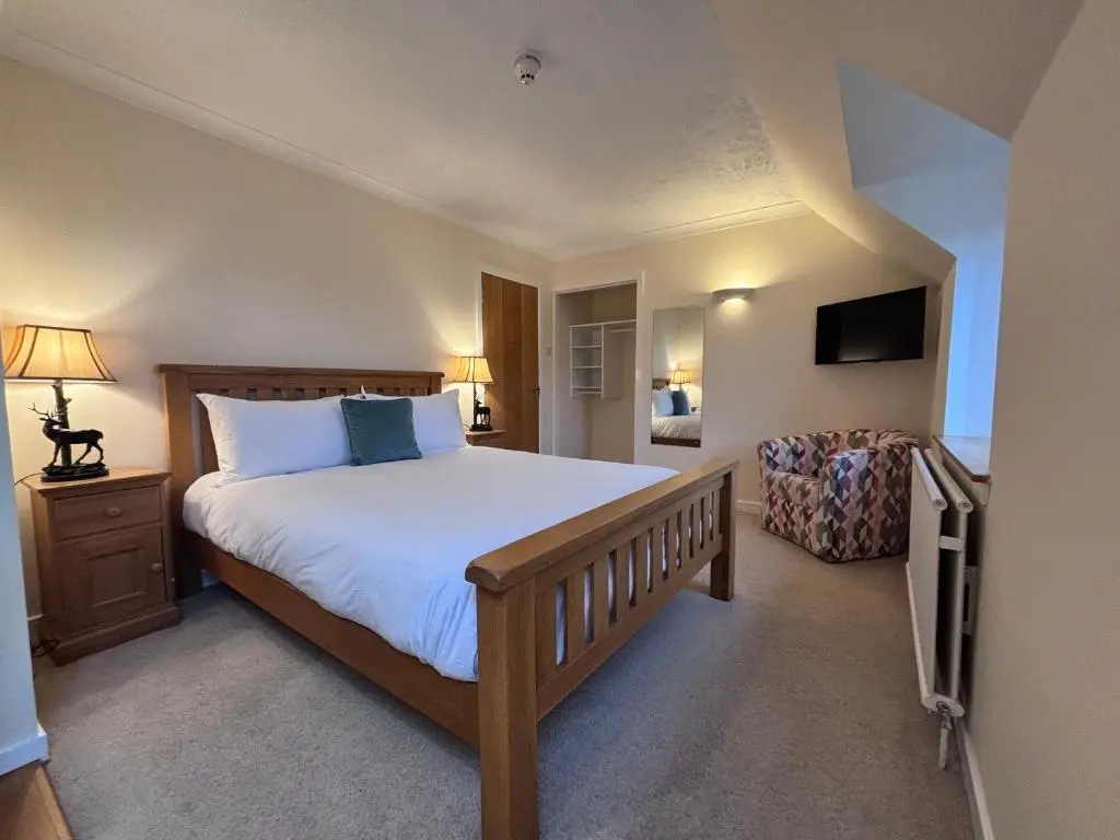 a bedroom with a large bed and a chair at The Ullapool Rooms in Ullapool