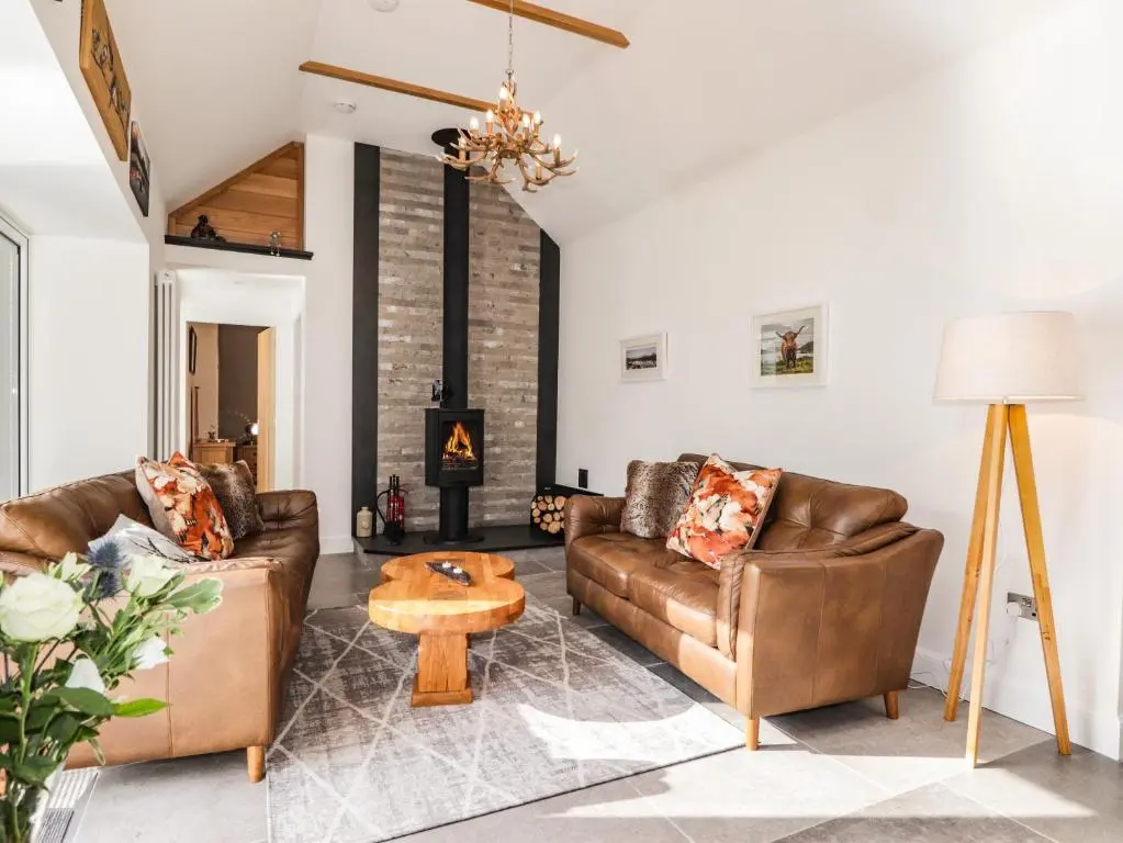 a living room with two leather couches and a fireplace at The Steading in Rogart