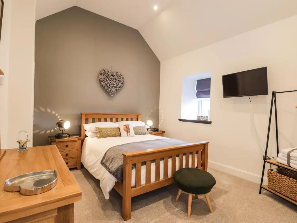 a bedroom with a bed and a tv on the wall at The Steading in Rogart