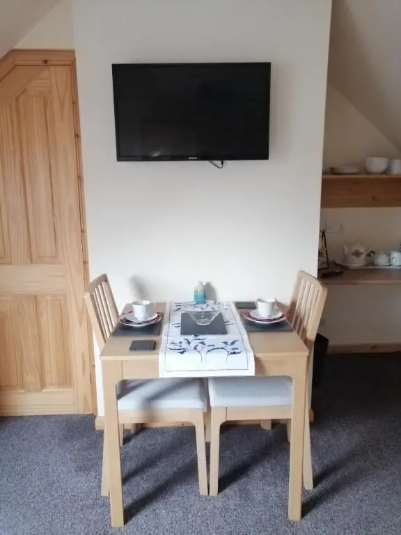 a table with two chairs and a television on a wall at Corrie View in Invergarry