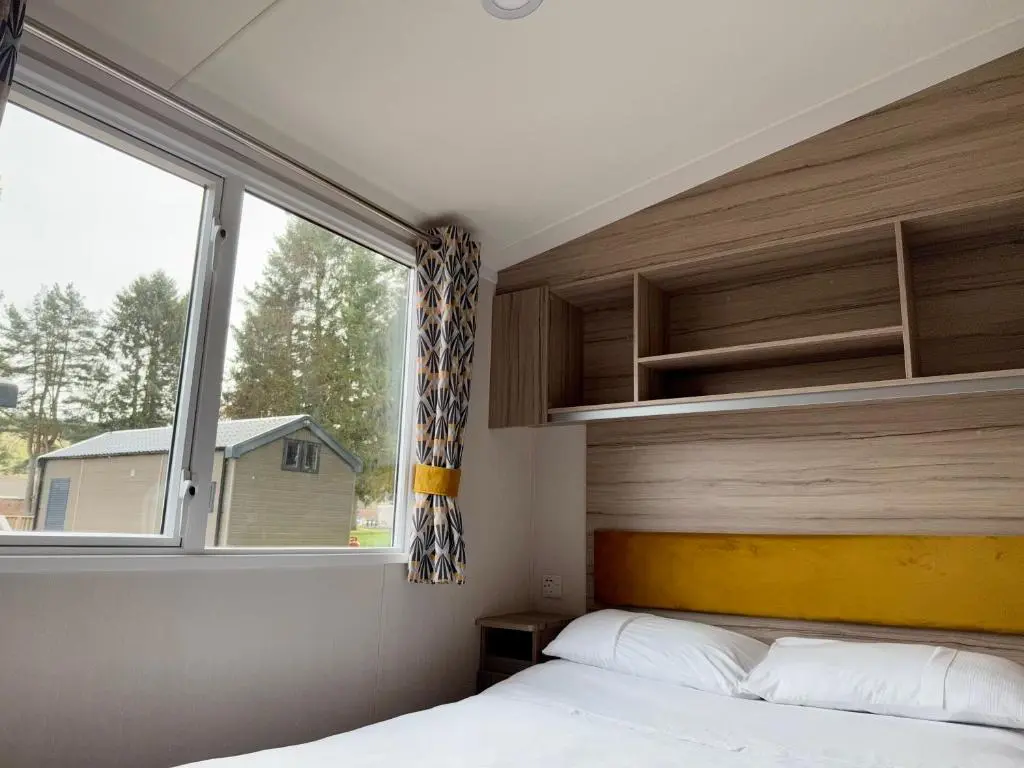 a bedroom with a bed and a large window at The Fly Van - Beautiful, luxury static caravan in Aberlour