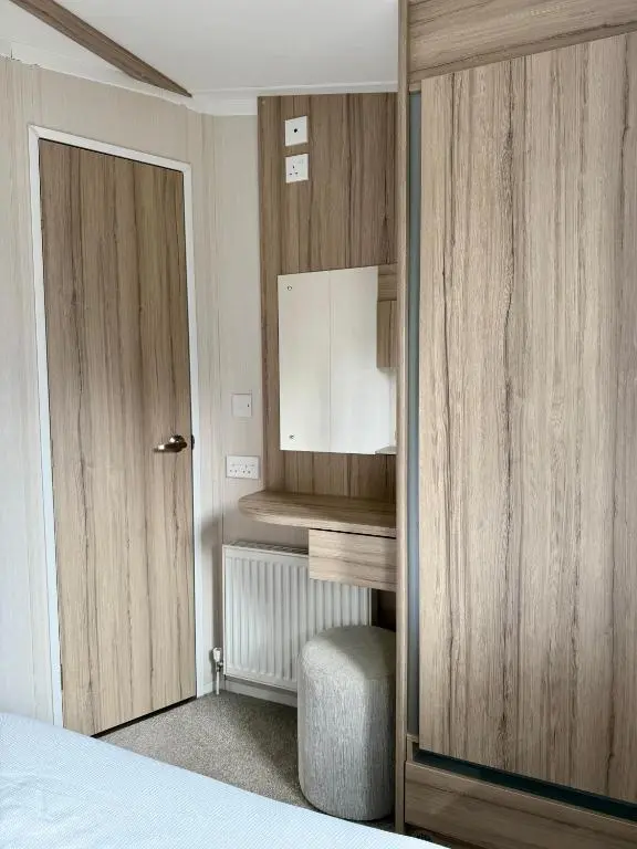 a bedroom with a bed and a door and a chair at The Fly Van - Beautiful, luxury static caravan in Aberlour