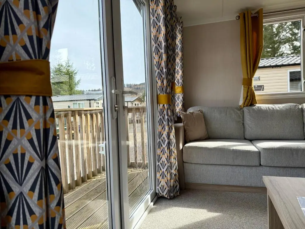 a living room with a couch and a balcony at The Fly Van - Beautiful, luxury static caravan in Aberlour