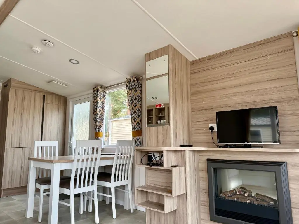 a dining room with a table and a tv and a fireplace at The Dram Van - Beautiful, luxury static caravan in Aberlour