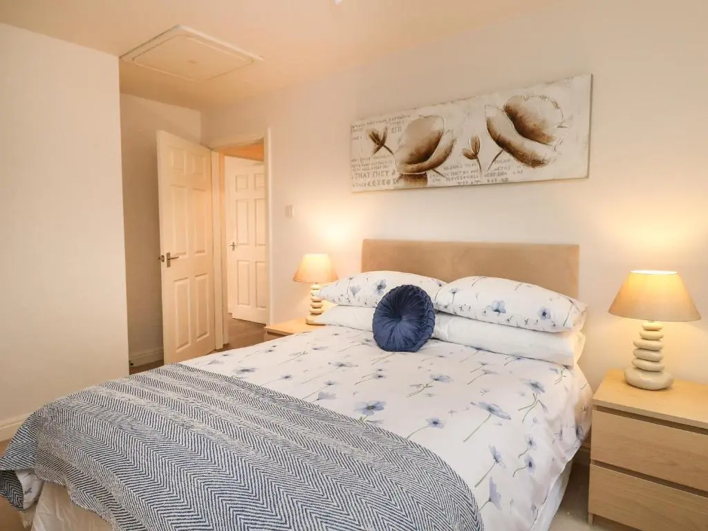a bedroom with a bed with blue and white sheets at 4 River Court in Invergarry
