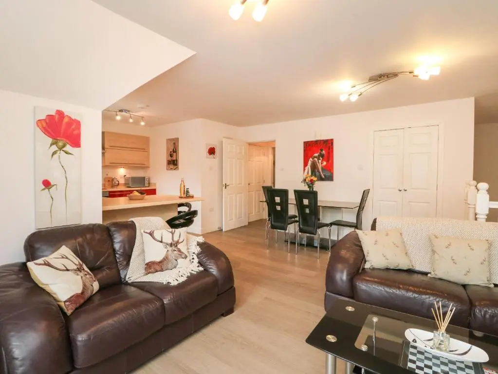 a living room with a leather couch and a table at 4 River Court in Invergarry