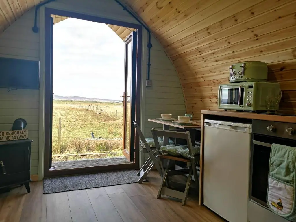 a kitchen with a microwave and a table and a window at Achmeney Glamping larger than Average pod in Halkirk