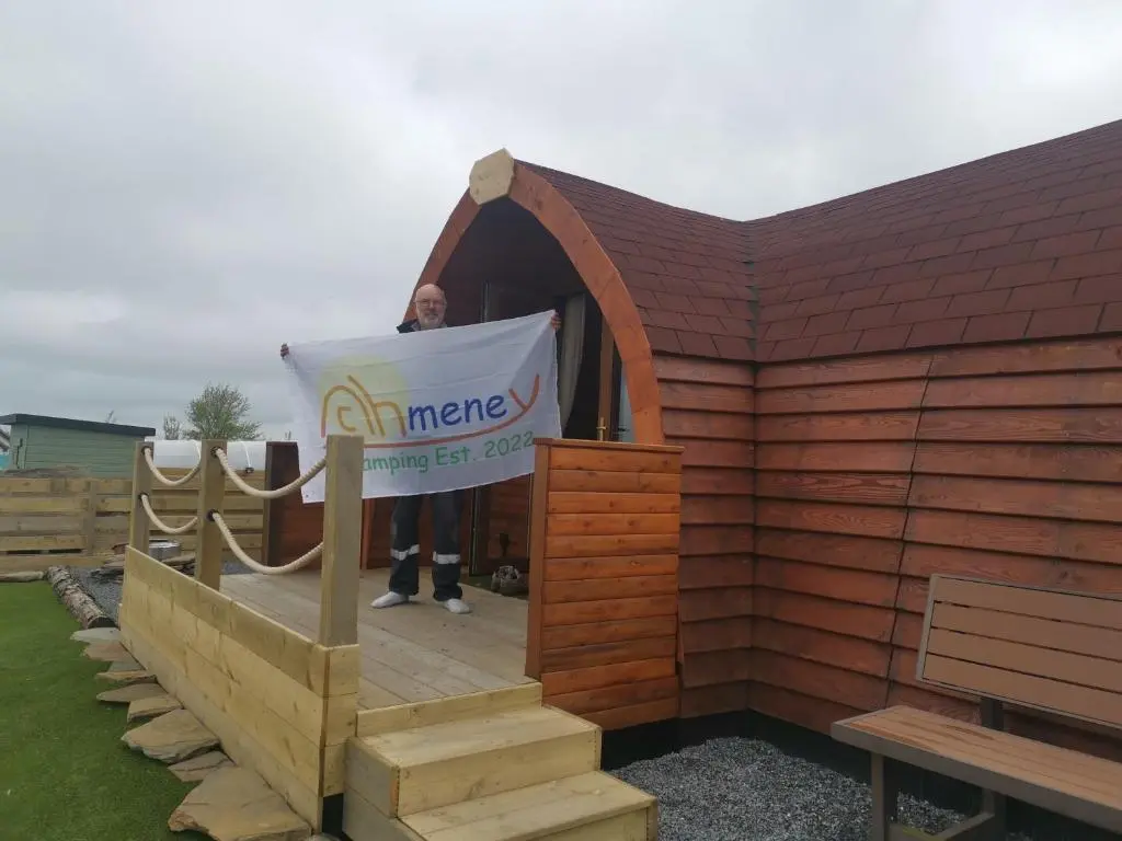 a man standing in a wooden building with a sign at Achmeney Glamping larger than Average pod in Halkirk