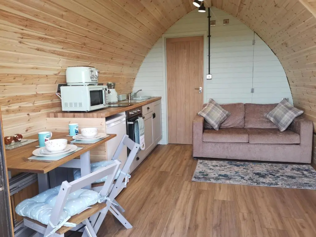 a kitchen and living room with a table and a couch at Achmeney Glamping larger than Average pod in Halkirk