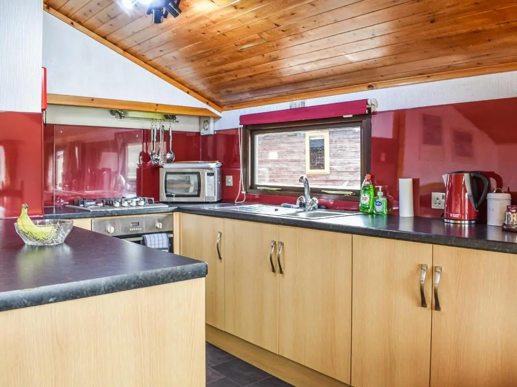 a kitchen with wooden cabinets and a counter top at 27 Aviemore Holiday Park in Aviemore