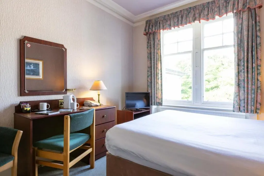 a hotel room with a bed and a desk and a window at The Highland Hotel by Compass Hospitality in Strathpeffer