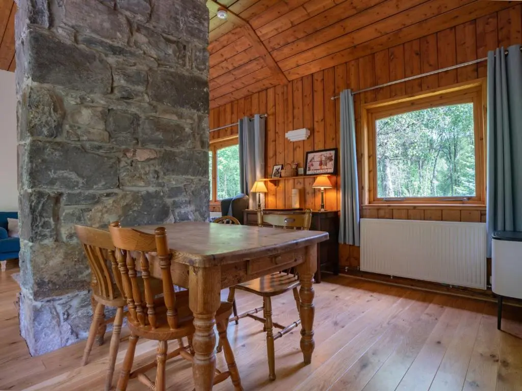 a dining room with a wooden table and a stone wall at Holiday Home Riverside Cottage by Interhome in Inverness