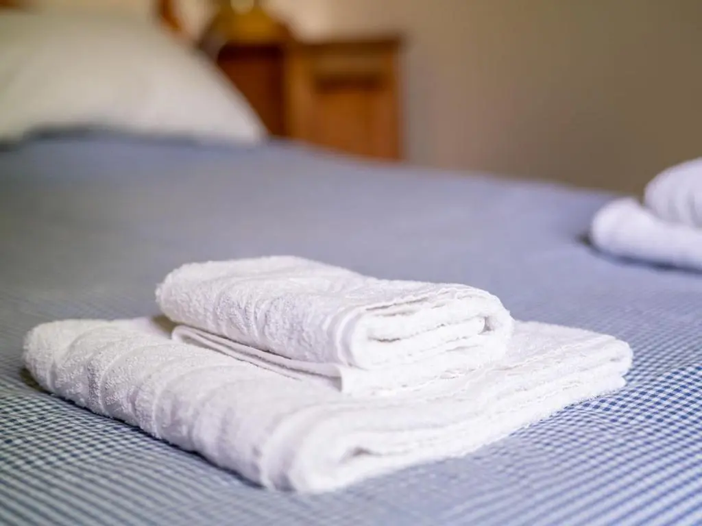 three white towels are stacked on a bed at Holiday Home Riverside Cottage by Interhome in Inverness