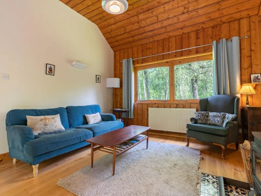 a living room with a blue couch and a table at Holiday Home Riverside Cottage by Interhome in Inverness