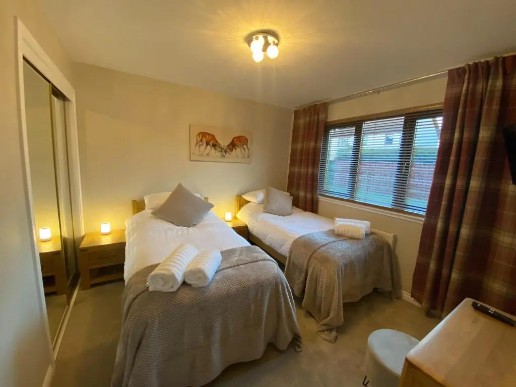 a hotel room with two beds and a window at discoverNESS Apartment in Inverness