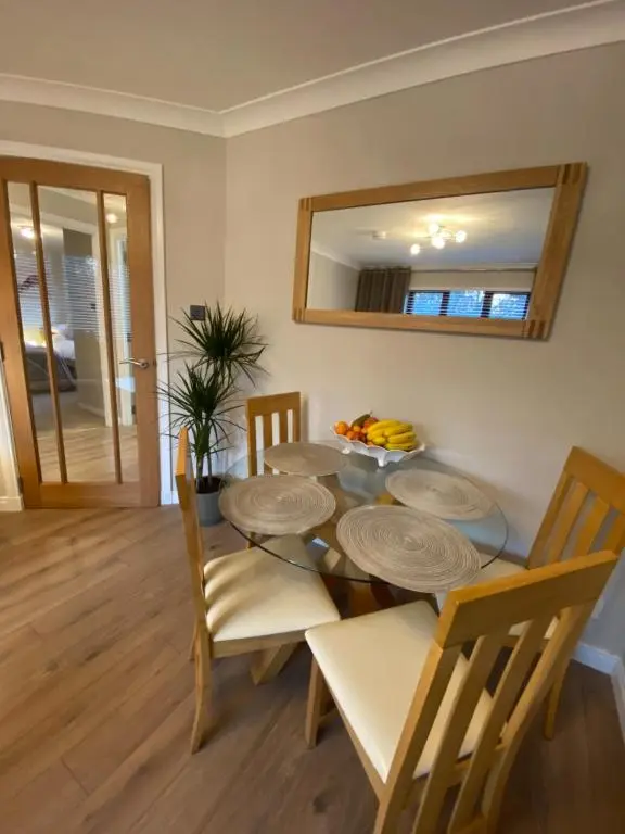 a dining room with a table and chairs and a mirror at discoverNESS Apartment in Inverness