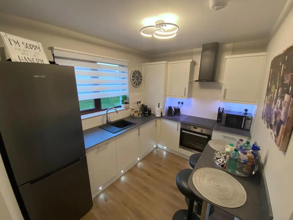 a kitchen with white cabinets and a black refrigerator at discoverNESS Apartment in Inverness