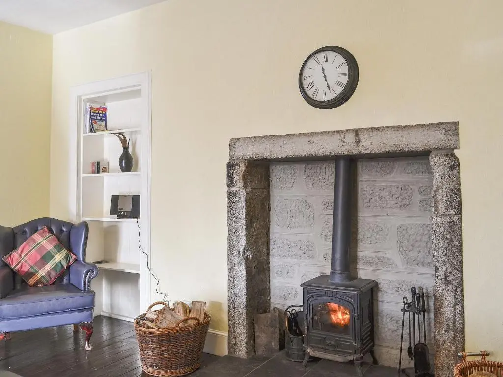 a living room with a fireplace with a clock on the wall at Treetops in Newtonmore