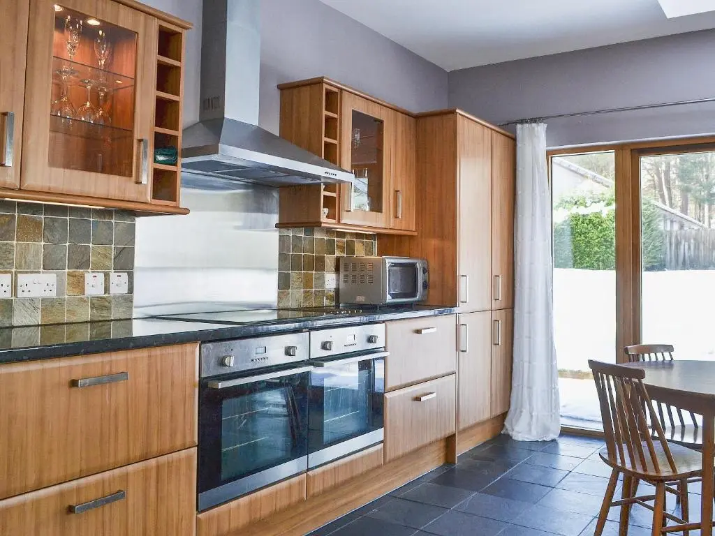 a kitchen with wooden cabinets and a stove top oven at Treetops in Newtonmore