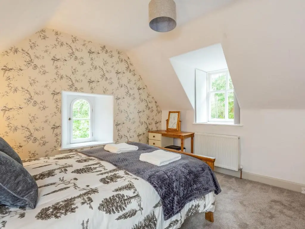 a bedroom with a bed and two windows at East Lodge in Contin