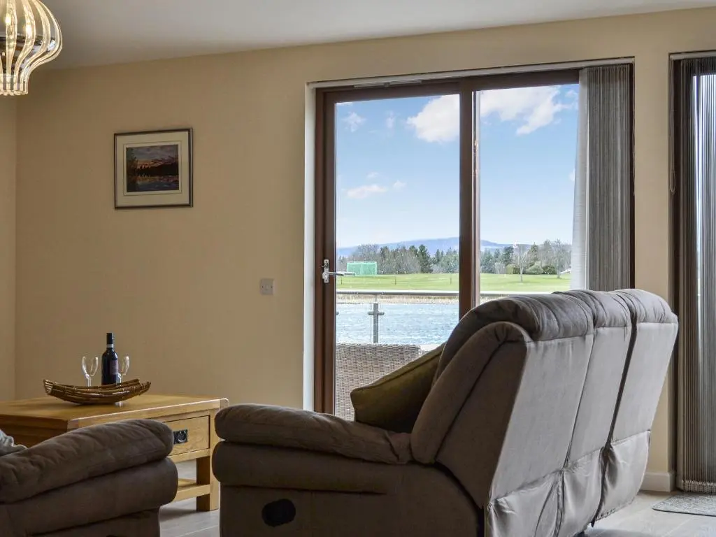 a living room with a chair and a sliding glass door at Golf View in Aboyne