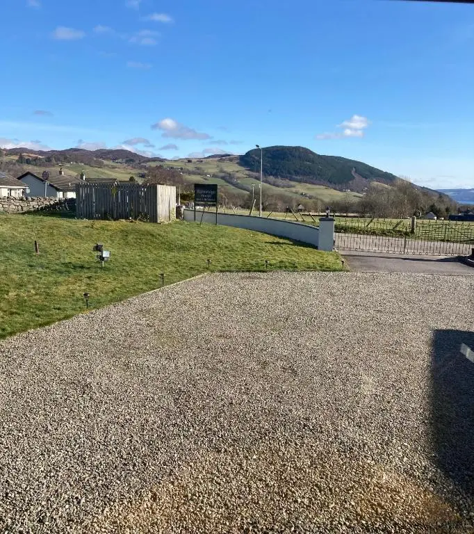 a road with a fence and a field of grass at Balmridge House, Loch Ness, Bed & Breakfast in Drumnadrochit