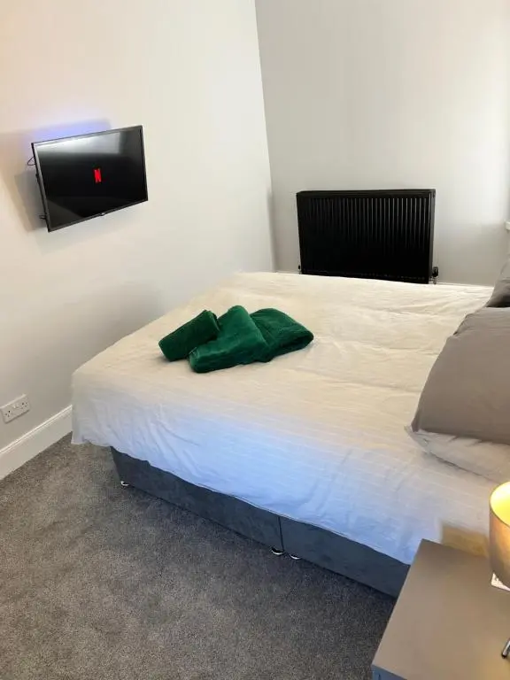 a bedroom with a bed with a green towel on it at Town centre 2 bed luxury apartment in Wick