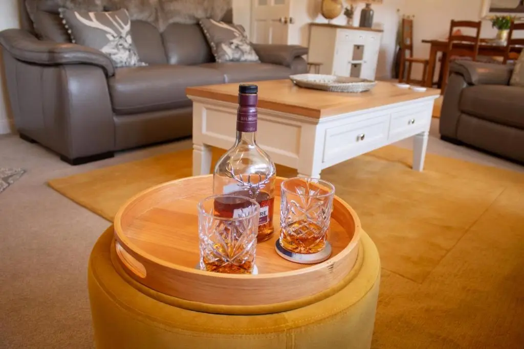 a bottle of wine and glasses on a table in a living room at Longfield, Daviot in Inverness