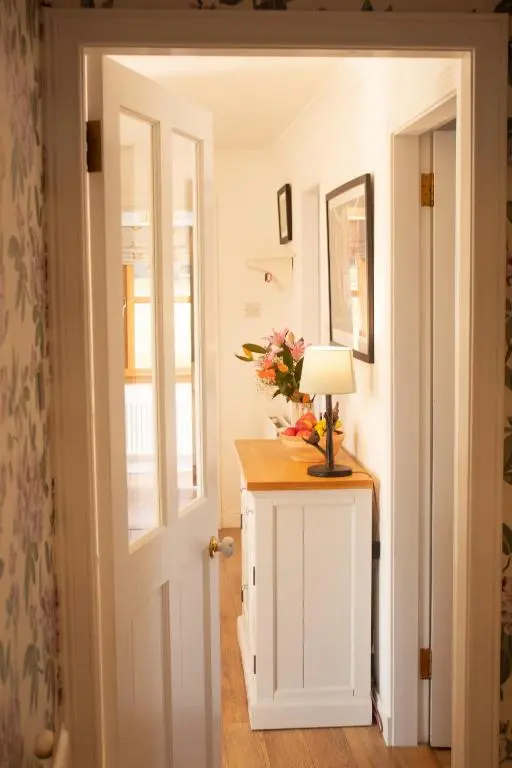 a hallway with a table with a lamp and flowers on it at Longfield, Daviot in Inverness