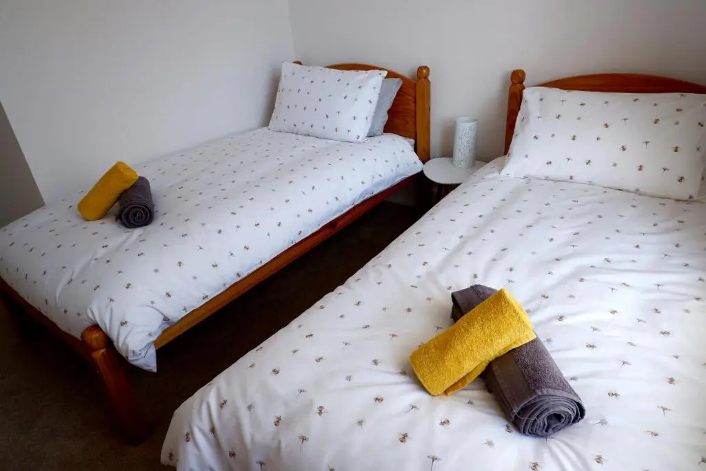 two twin beds in a room withskirts at No 7 Quiet, two bedroom Ground Floor Flat in Tornagrain Great for early Airport departures or late flights in Dalcross