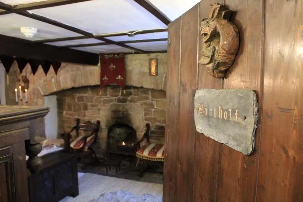 a living room with a stone fireplace with a sign on the wall at East Wing Lickleyhead Castle in Auchleven