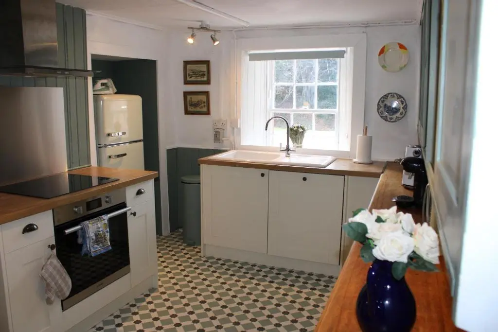 a kitchen with white cabinets and a sink and a window at East Wing Lickleyhead Castle in Auchleven