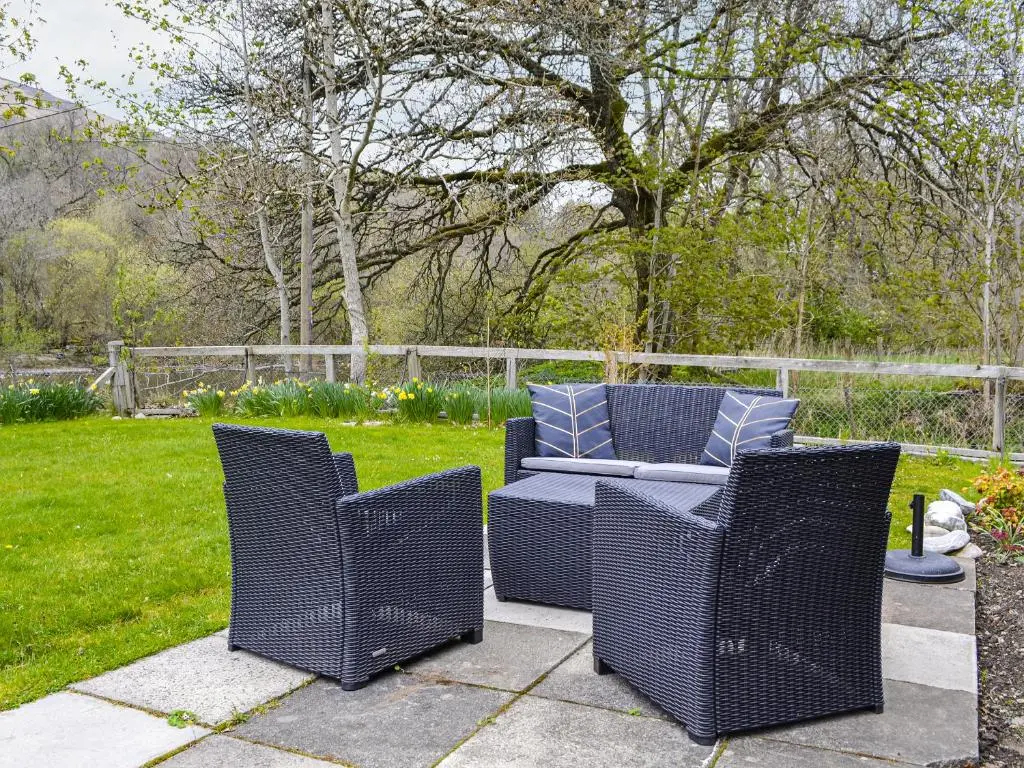 two wicker chairs and a table on a patio at Riverside Cottage in Blair Atholl