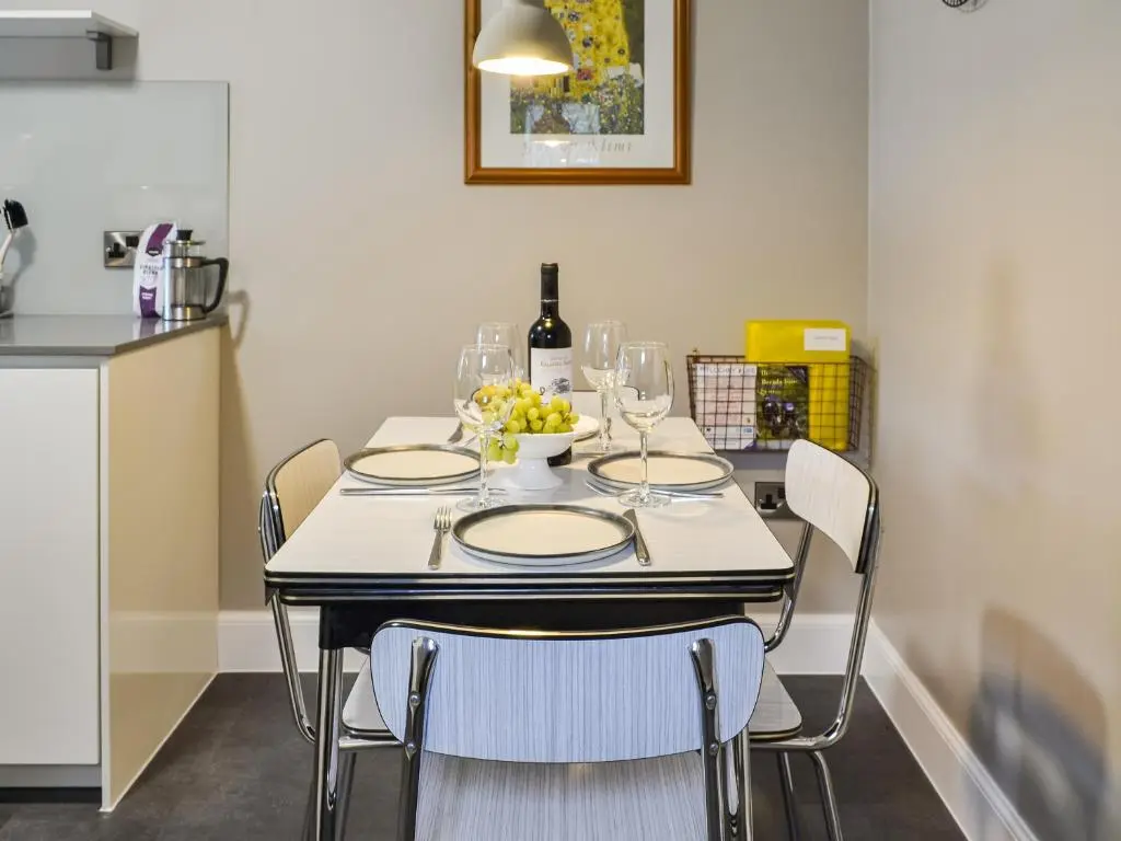 a table with wine glasses and a bowl of grapes on it at Riverside Cottage in Blair Atholl
