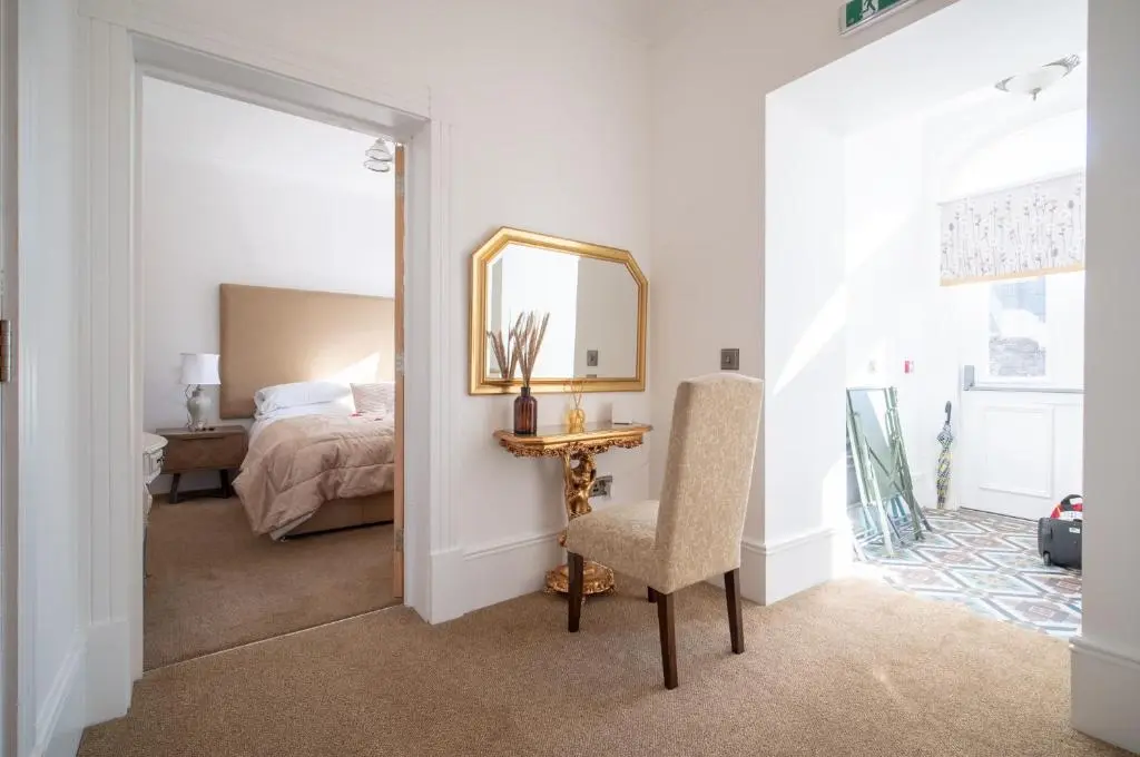 a bedroom with a mirror and a chair and a bed at Gordonston Apartments in Inverness