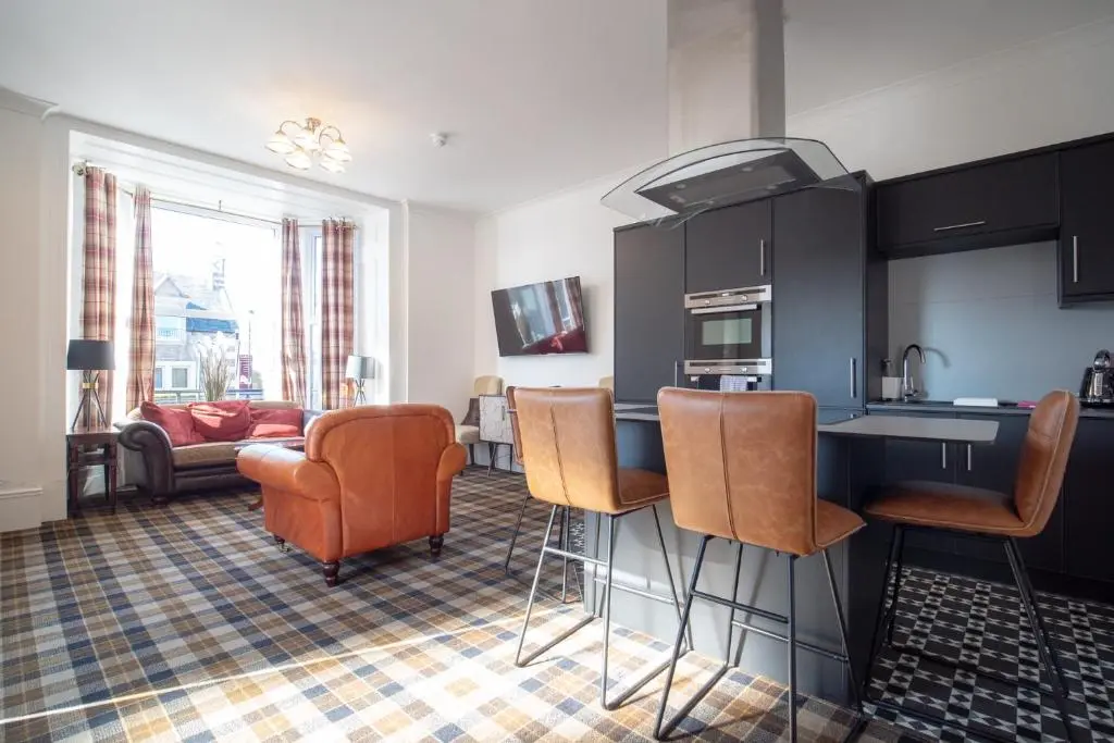 a kitchen with black cabinets and orange chairs at Gordonston Apartments in Inverness