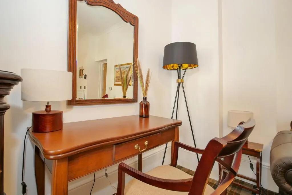 a desk with a mirror and a chair and a lamp at Gordonston Apartments in Inverness