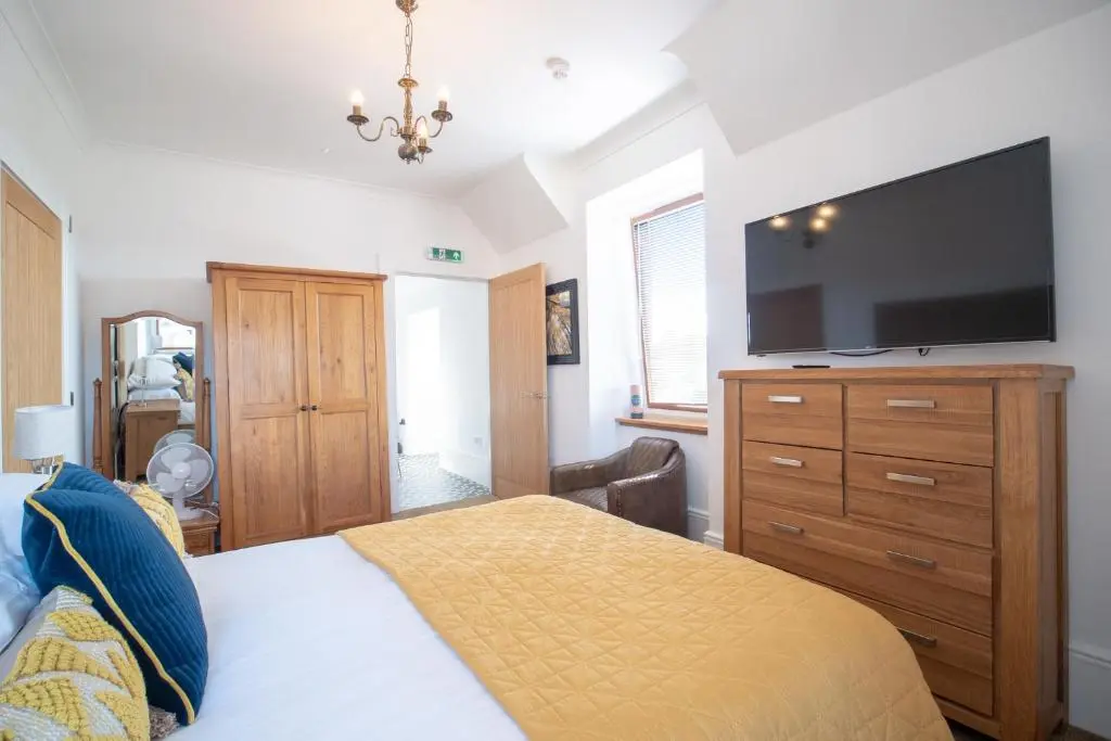 a bedroom with a bed and a flat screen tv at Gordonston Apartments in Inverness