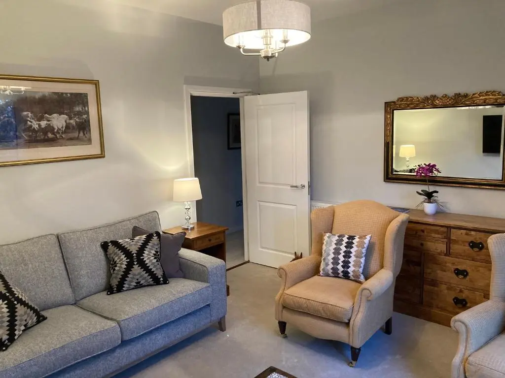 a living room with a couch and a chair and a mirror at Hedgefield House - Serene Top Floor Flat in Inverness