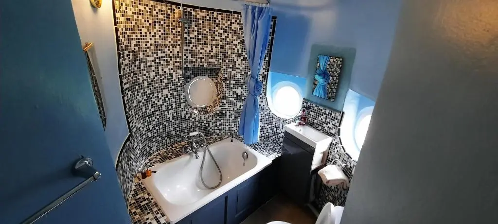 a bathroom with a tub and a round mirror at West Wing Lickleyhead Castle in Auchleven