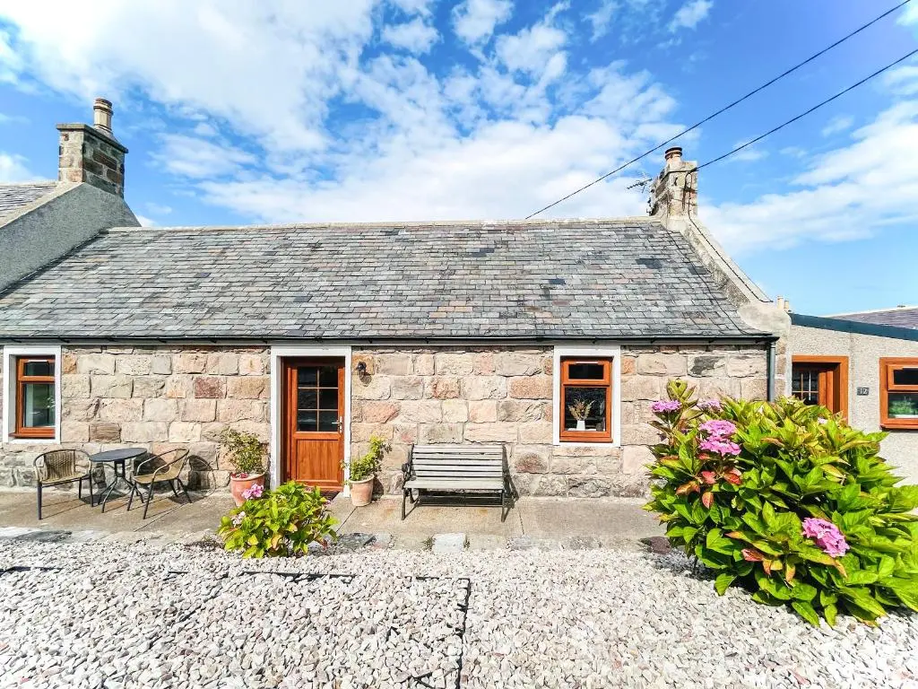 a stone house with a bench in front of it at Portknockie Escape in Portknockie