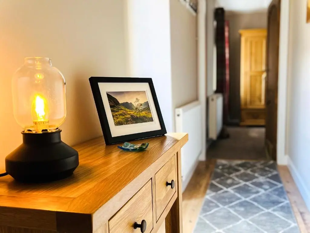 a lamp on top of a wooden dresser with a picture at Portknockie Escape in Portknockie