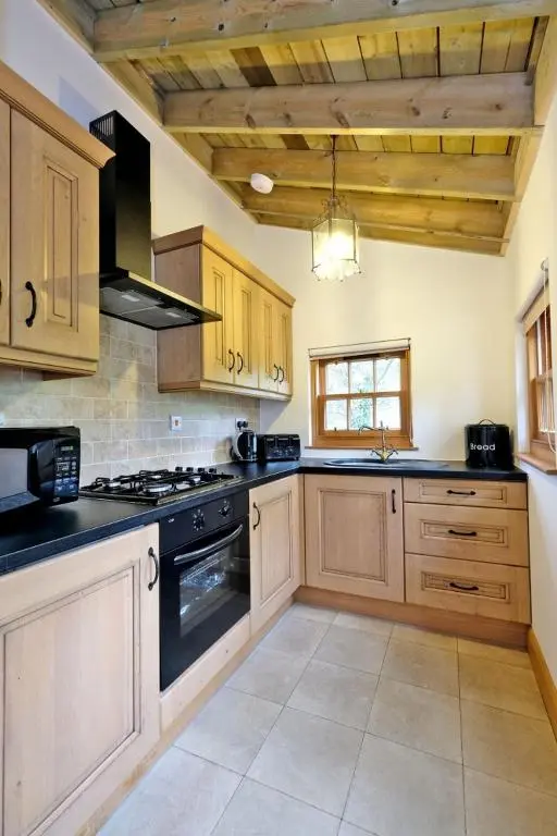 a kitchen with wooden cabinets and a stove top oven at Entire unique tiny house - Moss Cabin in Banff