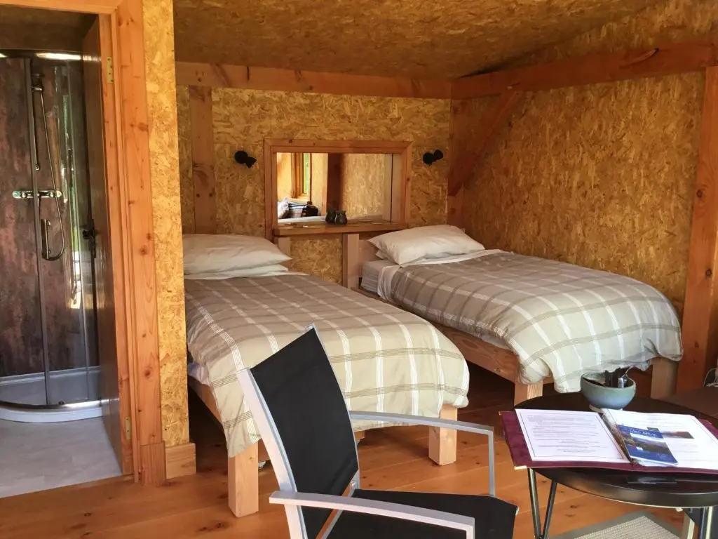 two beds in a room with a table and a chair at Caledonian Glamping in Cannich
