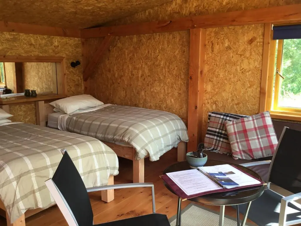 a bedroom with two beds and a table and chairs at Caledonian Glamping in Cannich