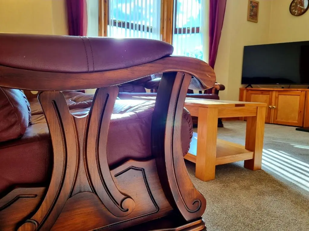 a wooden chair in a living room with a table at Inverness City 3 bedroom house free parking in Inverness