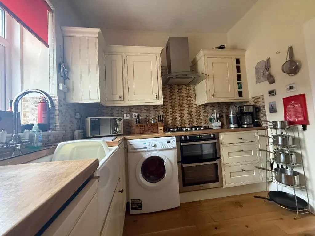 a kitchen with white cabinets and a washing machine at Riverside Cottage City Centre in Inverness