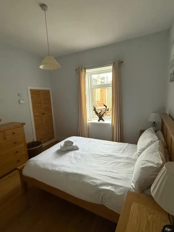 a bedroom with a large white bed and a window at Riverside Cottage City Centre in Inverness
