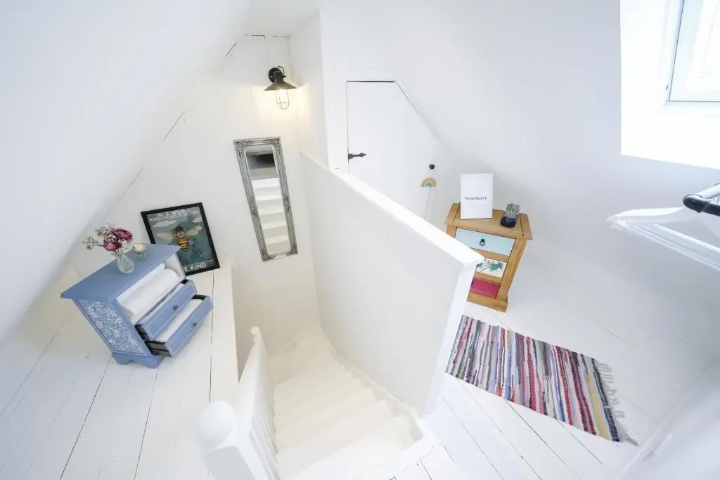 a white staircase with a mirror and a rug at The Wee House by the Sea in Balintore